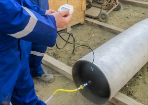 Measuring device testing a large metal pipe