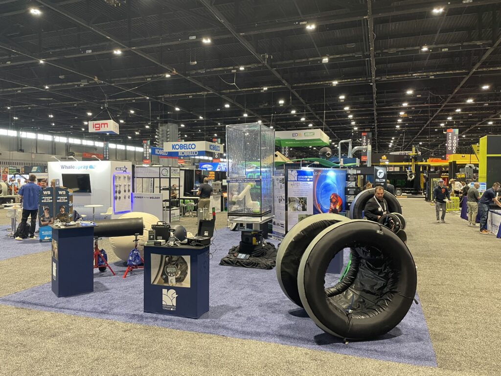 Indoor industrial exhibition with various displays and booths.